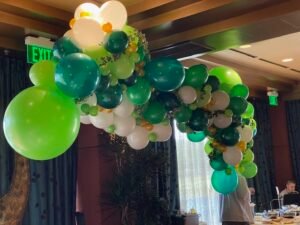 Green and white balloon arch decoration indoors.