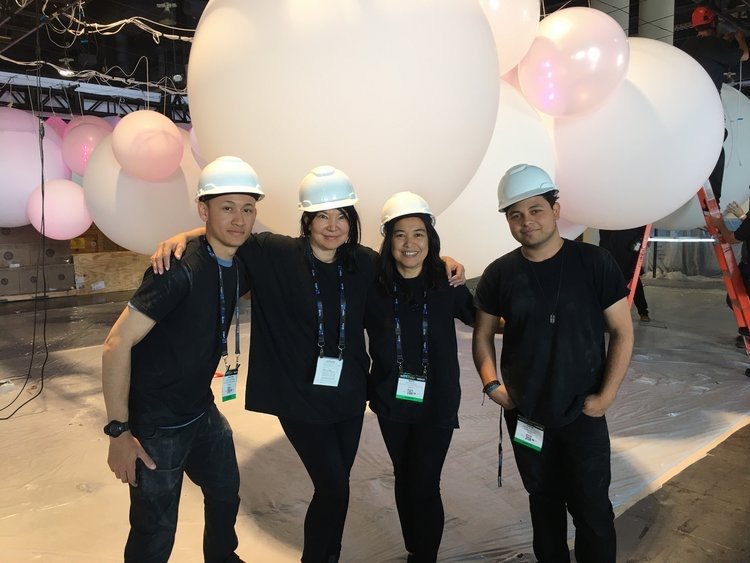 Four people in hard hats under balloons. Four people in hard hats under balloons.
