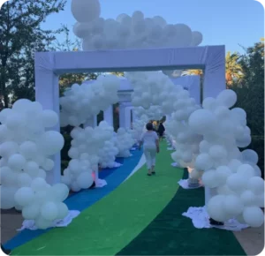 White balloon archway over green and blue path.