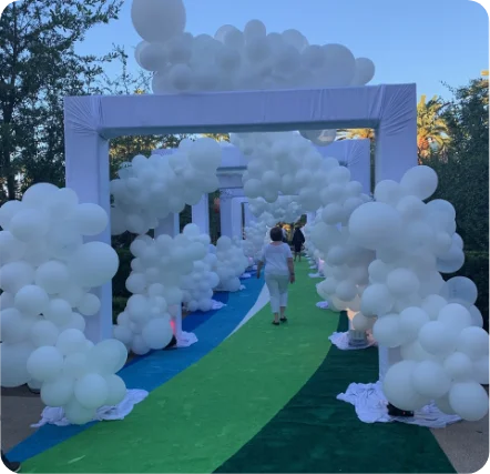 White balloon archway over green and blue path.