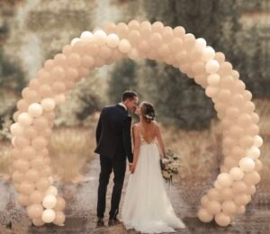 Bride and groom under balloon arch outdoors.