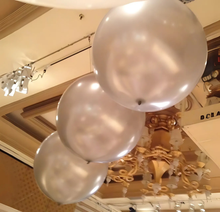 Silver balloons under ornate ceiling lights.