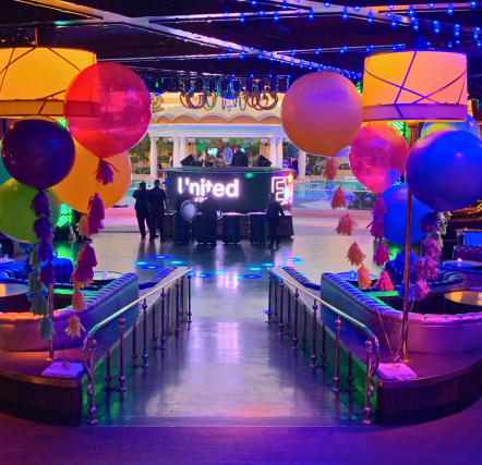 Colorful party venue with balloons and lights.