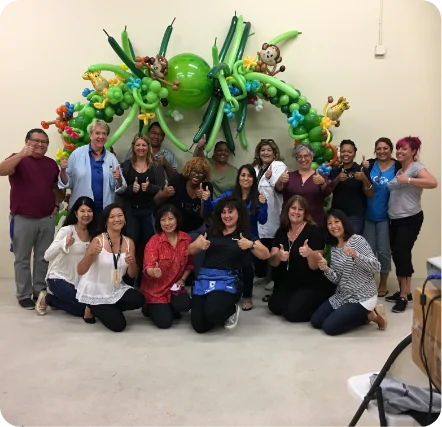 Group posing with colorful balloon arch.