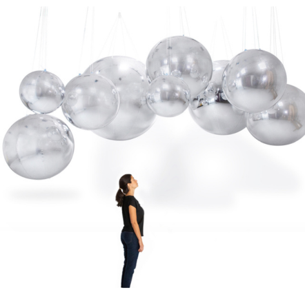 Woman looking at large silver hanging spheres.