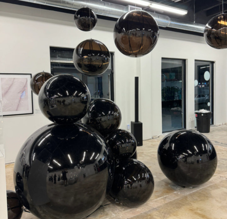 Black reflective spheres in a modern gallery.