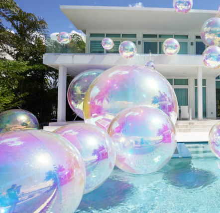 Large iridescent bubbles floating by modern house.