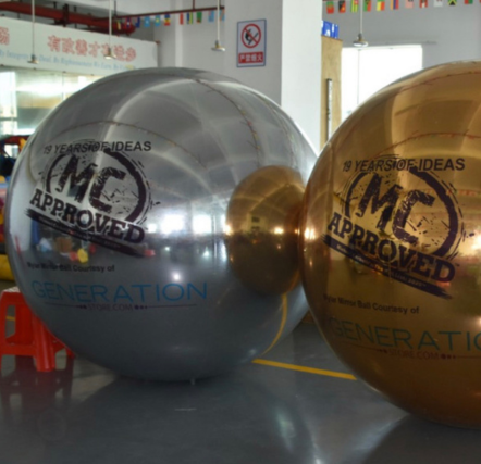 Silver and gold inflatable balls with text.